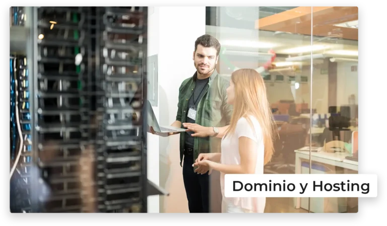 Dos personas de pie en una sala de servidores con una laptop